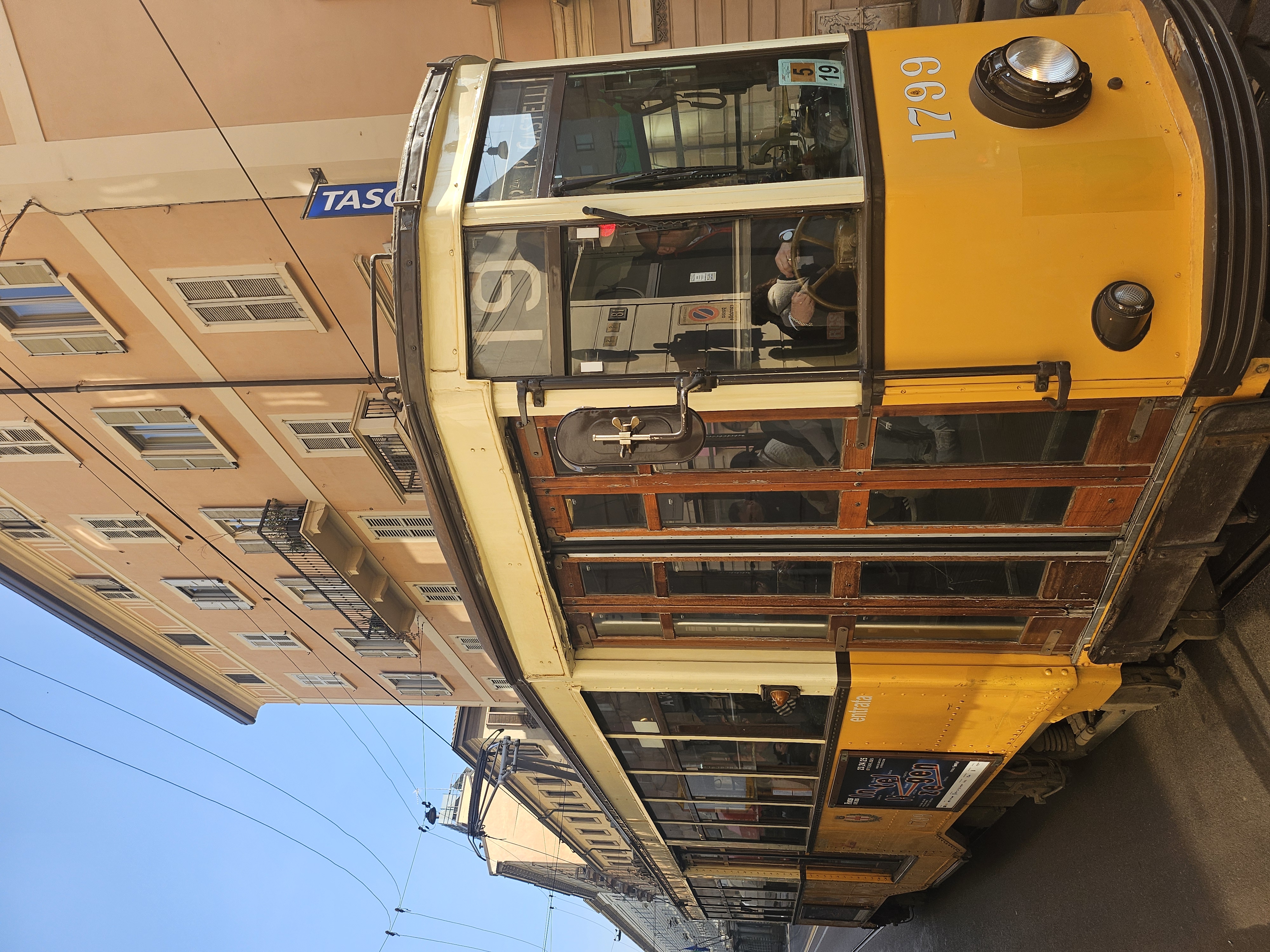 Iconic vintage yellow Milanese tram clattering through historic stone streets