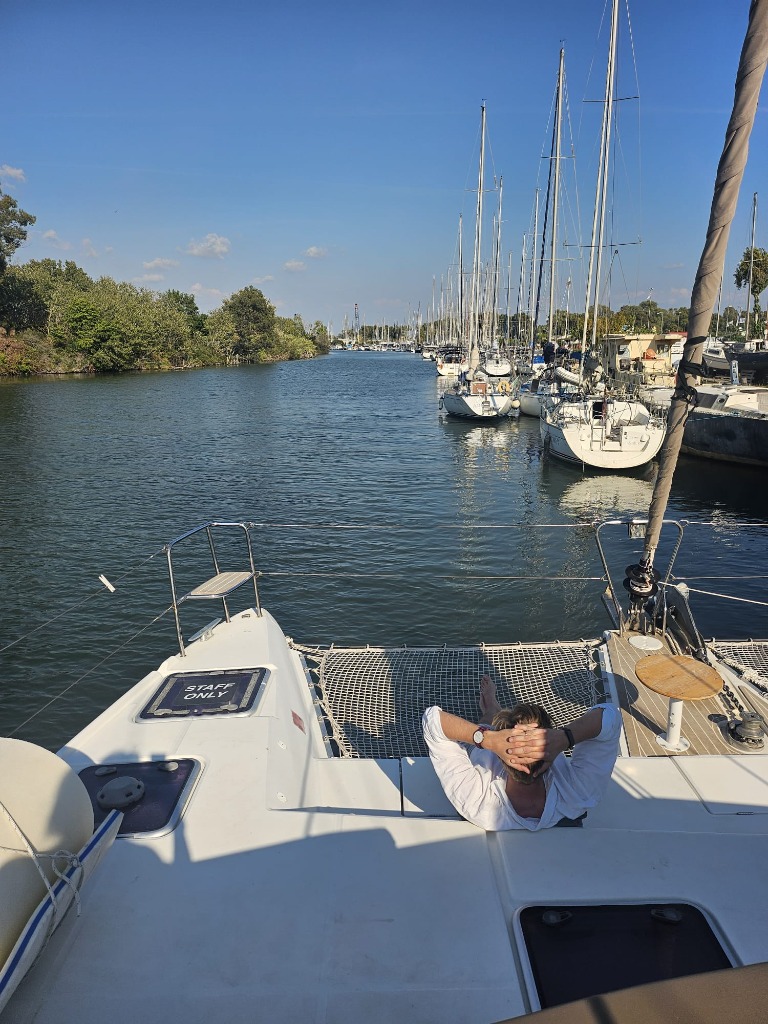 Relaxing on the front nets of a catamaran yacht under Mediterranean blue sky